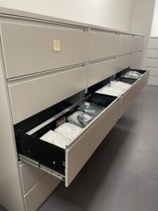 A long chest of drawers with one drawer open showing clothing