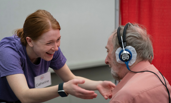 A volunteer named Catherine helps a man undergoing a hearing test