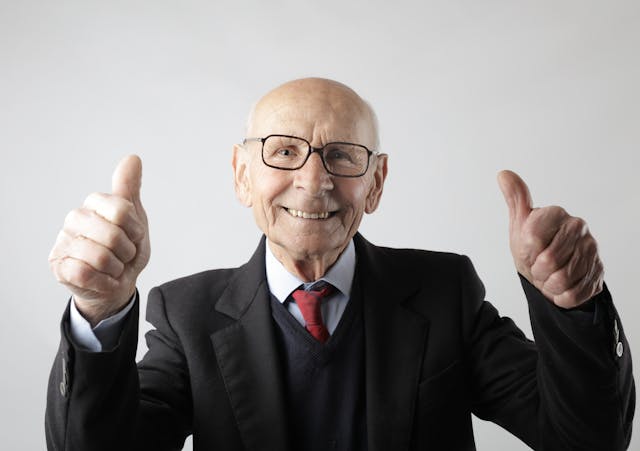 Senior man in glasses holding two thumbs up
