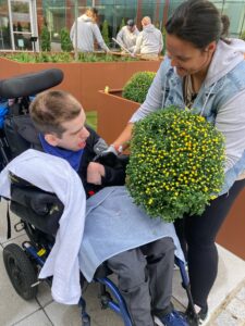 woman handing plant to male in wheelchair 