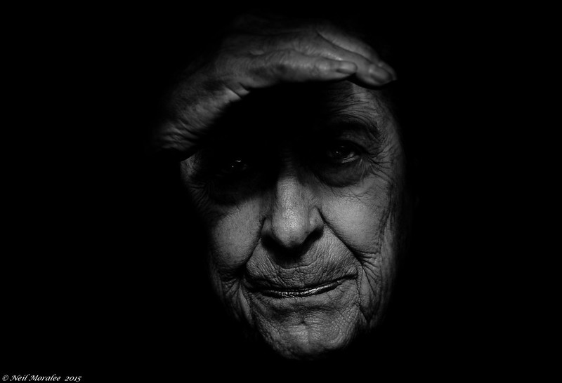 black and white photo of elderly woman with a hand over her eyes, creating a shadow