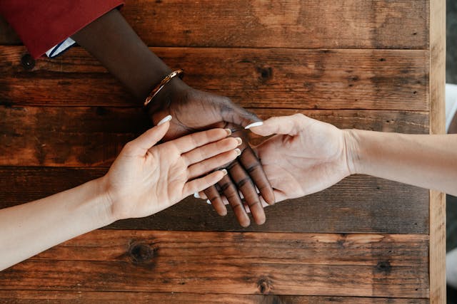 diverse women stacking hands on a wooden table