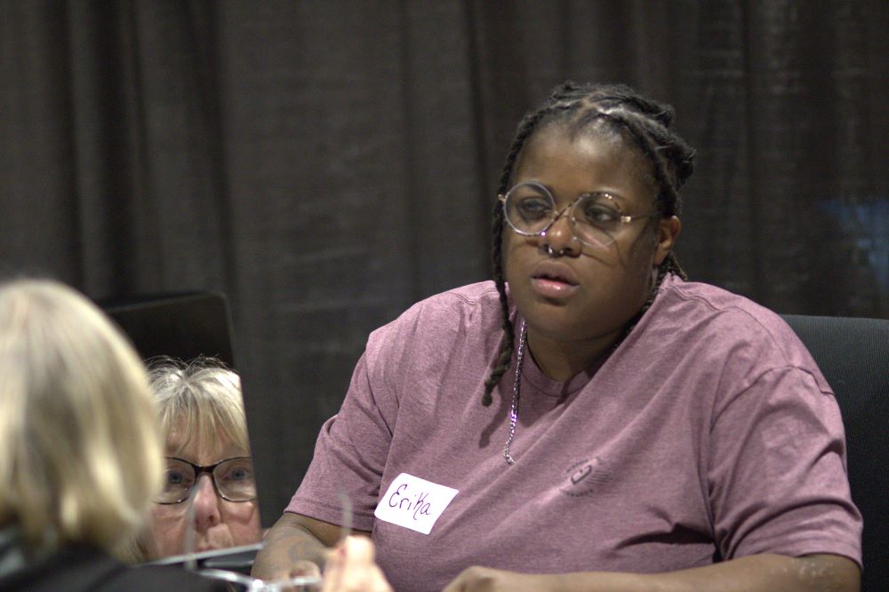 A woman trying eyeglasses at Mission of Mercy as a volunteer looks on