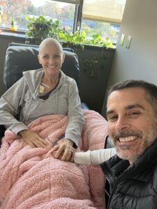 Tracy getting chemo, holding hands with her husband