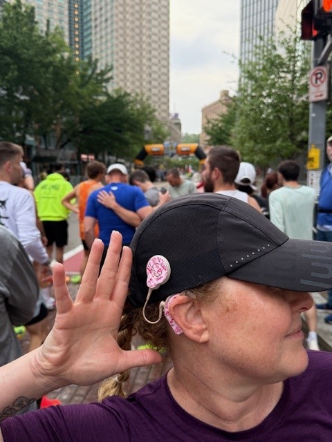 Sally at a race with a cap on and her CI visible