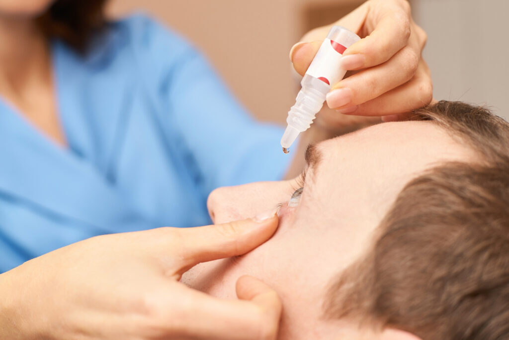 Ophthalmologist applying eye drops by holding patient's eye open
