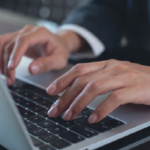 A male's hands typing on a laptop