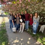 The Cunningham Lab in a group photo taken outside on a sidewalk by some flowering trees