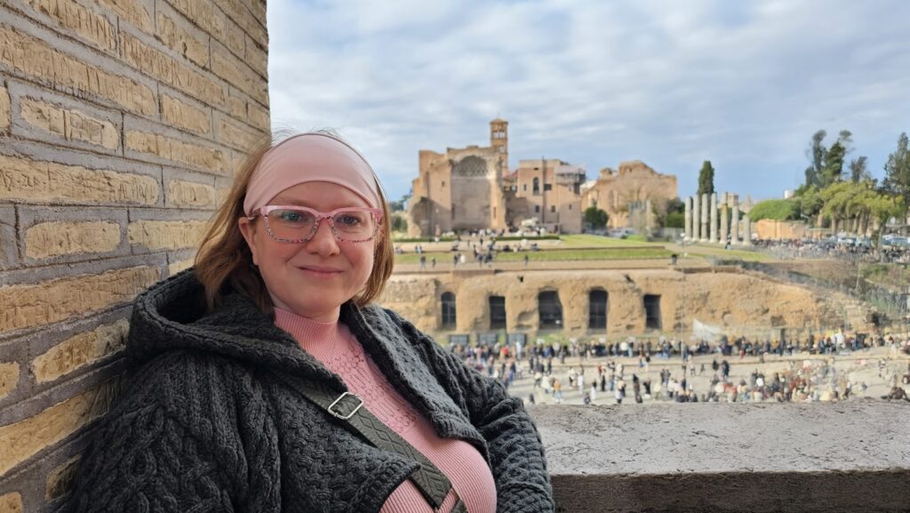 Kelly McSorley leaning against a wall with ruins in the background